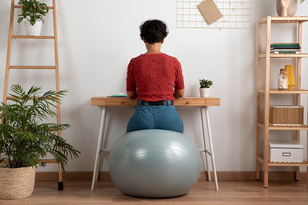 Woman sitting on ball chair while working from home