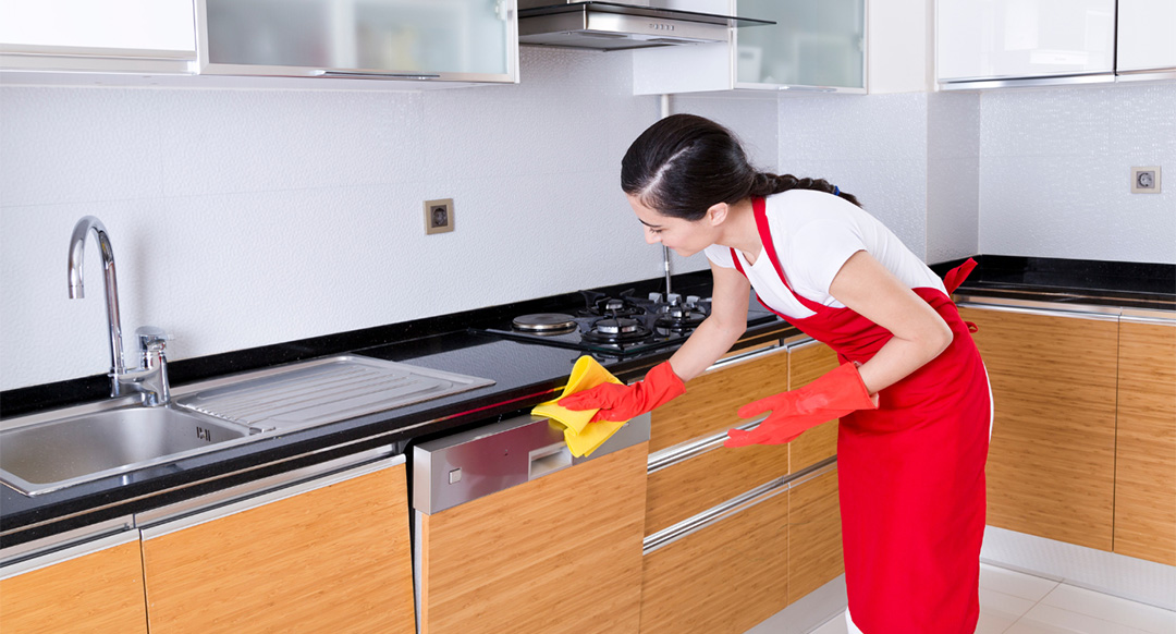 Woman wearing red apron and gloves cleaning the dishwasher